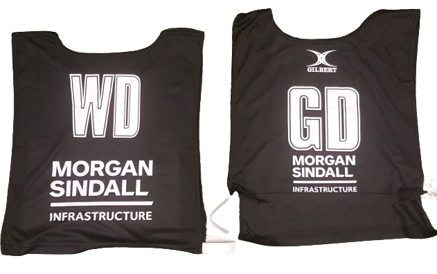 Two black Personalised Gilbert Netball Bibs (Reversible) labeled “WD” and “GD” in white, both featuring the Morgan Sindall Infrastructure and Gilbert logos above the position labels.