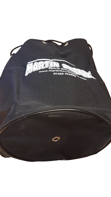 The Martin Berrill Sports Ball Duffle Bag is a large black duffle with white text and logo, shown from a low angle highlighting its round base—perfect for convenient sports ball storage.