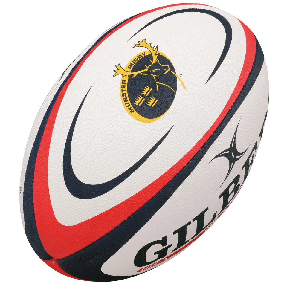The Gilbert Munster Replica Rugby Ball is a white training ball with red and navy stripes, featuring the Munster Rugby Club logo in yellow and black, and "Gilbert" branded in bold letters.
