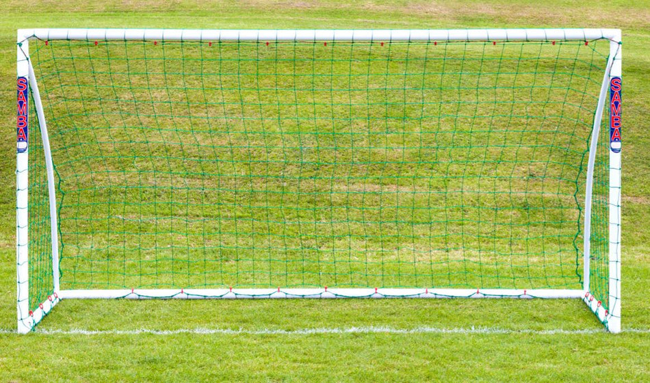 A Samba Sports Samba Trainer Goal 16 x 7, featuring green netting and "SAMBA" in red on each post, stands on a grassy field with some brown patches in the background.