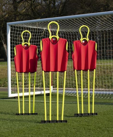 Three Samba Sports Pep Pro Mannequins (set of 3, with carry bag) are positioned in front of a soccer goal on grass, ideal for free kick training. Trees and netting appear in the background.
