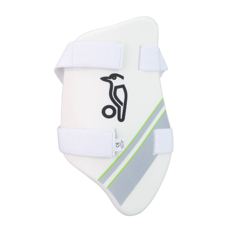 The Kookaburra 1000 Thigh Pad is a white pad with an absorbent towel back, two adjustable Velcro straps, a black kookaburra logo above a cricket ball, and a diagonal grey and green stripe.