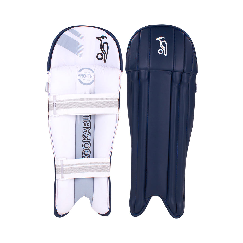 A pair of Kookaburra 4.0 T20 Wicket Keeping Pads in navy: one displays the white Kookaburra logo on the front, the other shows cushioned white padding and two straps at the back, offering superior impact protection.