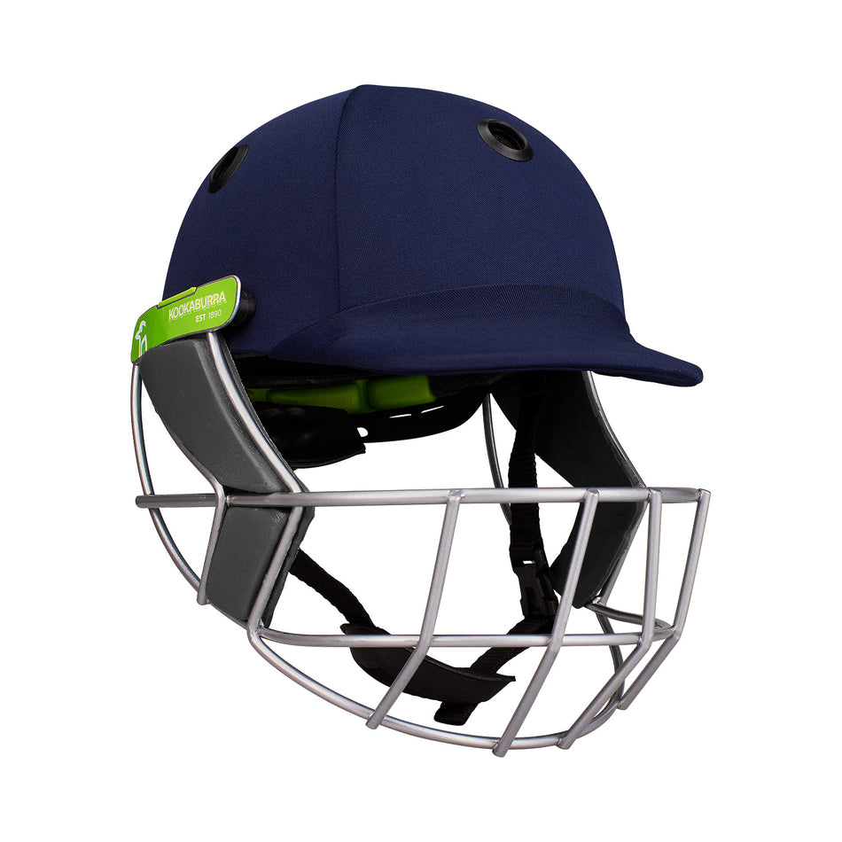 The Kookaburra Pro 1500 Junior Helmet by Kookaburra is a navy blue cricket helmet with a lightweight build, titanium faceguard, grey side padding, top ventilation holes, and a green logo tag.