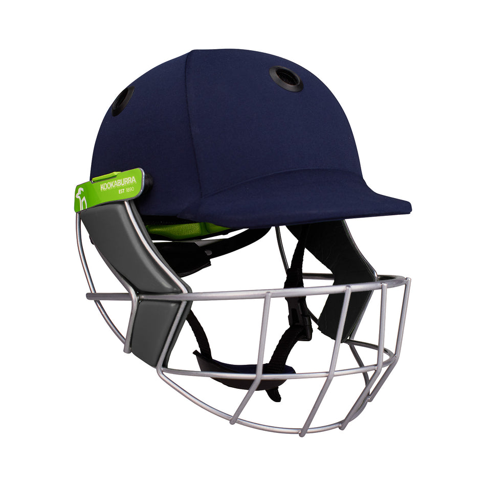 The Kookaburra Pro 1200 Junior Helmet is a navy blue, lightweight cricket helmet with a steel faceguard, black chin straps, and a green Kookaburra brand tag on the side—ideal for young players.