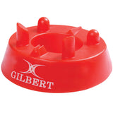 The Gilbert 320 Precision Kicking Tee is a red moulded rubber tee from Gilbert, featuring four raised prongs and a white Gilbert logo on the side, designed for accurate rugby kicking.