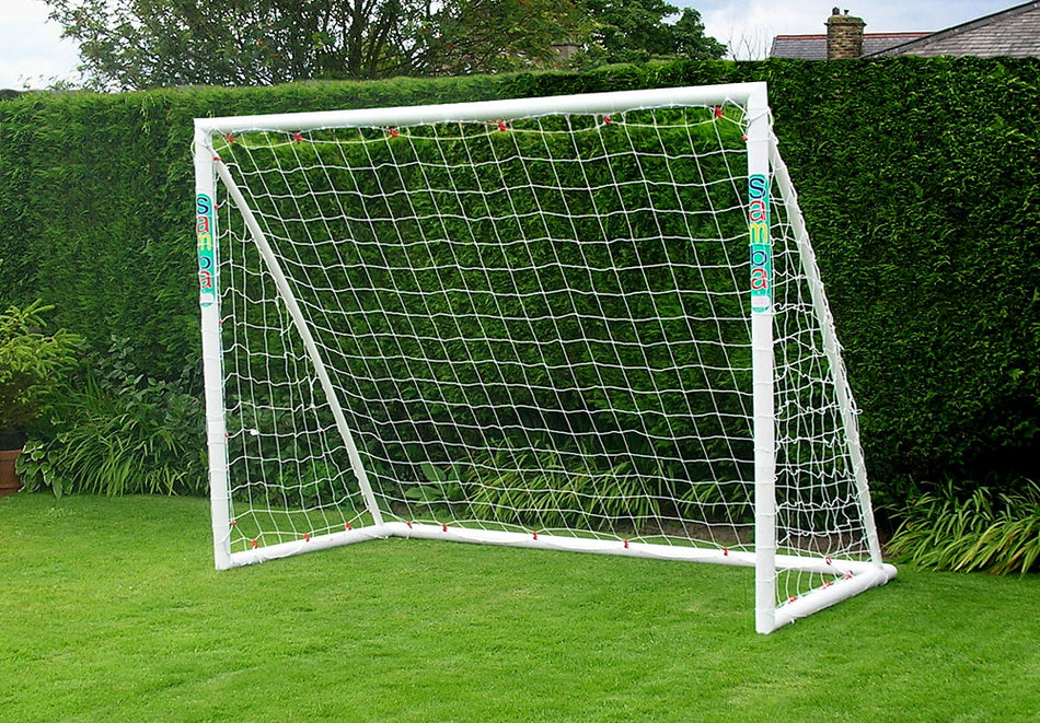 The Samba Sports Samba Trainer Goal 8 x 6, a white freestanding uPVC football goal with net, is set up on a green lawn—ideal for outdoor play in the garden.