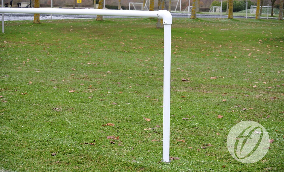 A Harrod Sport 2.1M Spectator Barrier Starter, built from white galvanised steel, forms a right angle over green grass with brown leaves; blurred grass and trees in the background hint at its use in a barrier system.