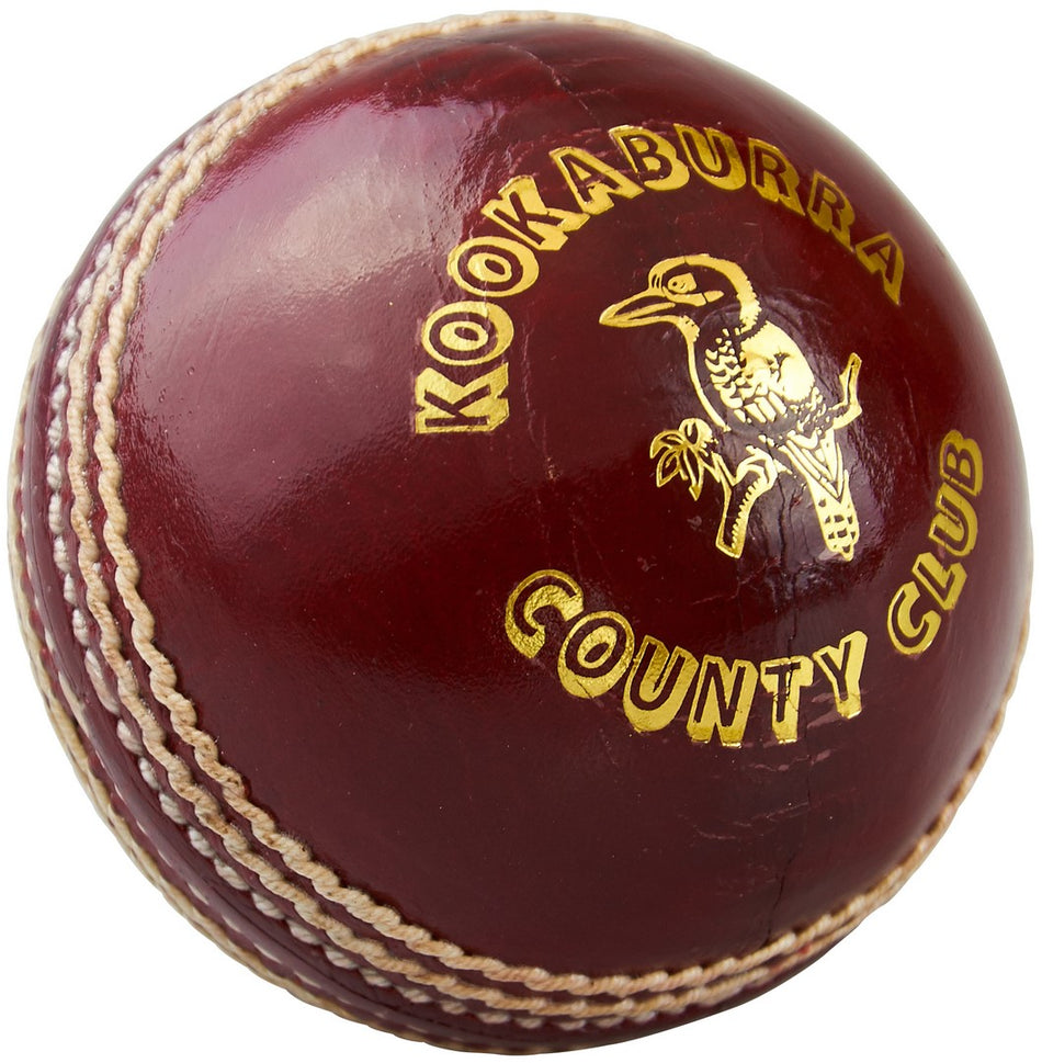 A close-up of the Kookaburra County Club Cricket Ball shows its durable hand stitching, white seams, yellow Kookaburra County Club logo, and a kookaburra bird illustration on the surface.