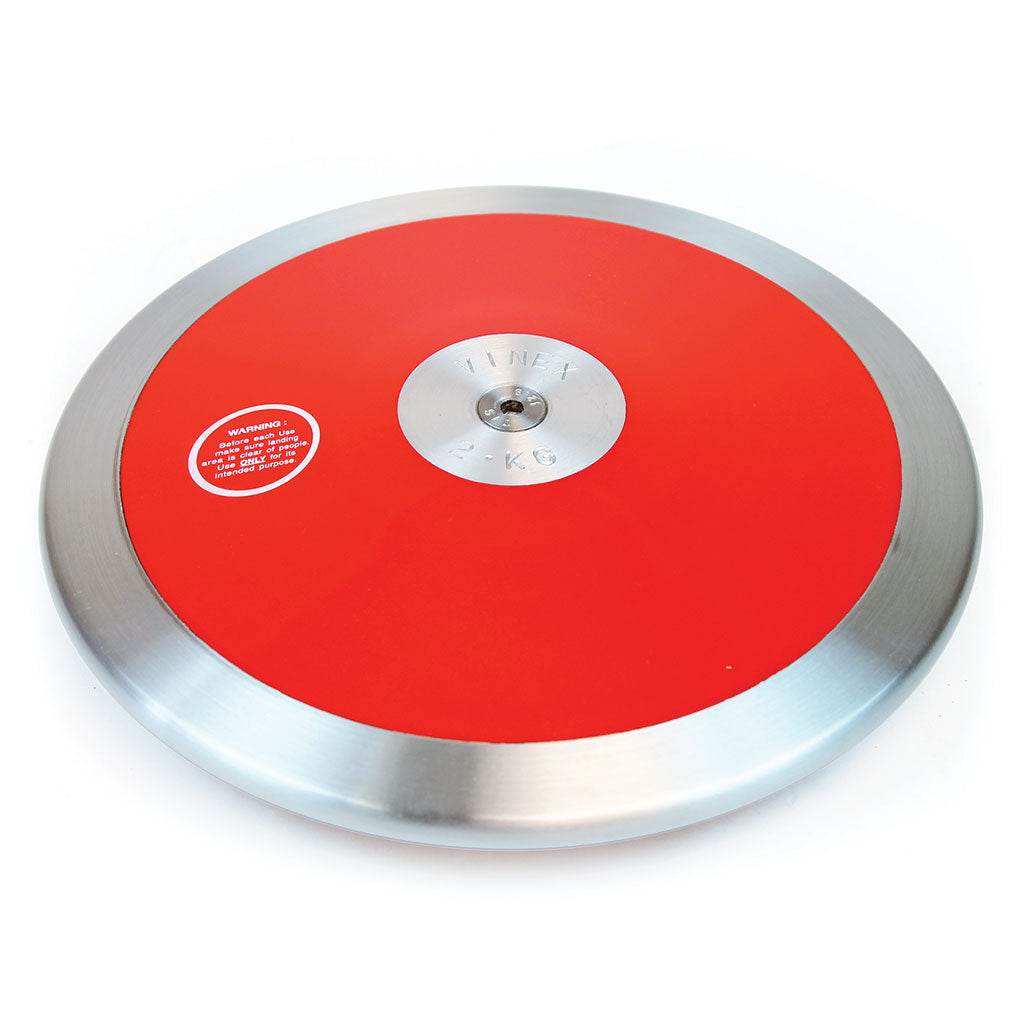 The Mastersport Club Discus features a red and silver steel rim, a metallic engraved center, and a warning label on the red surface. Ideal for school competitions or training sessions in track and field events.
