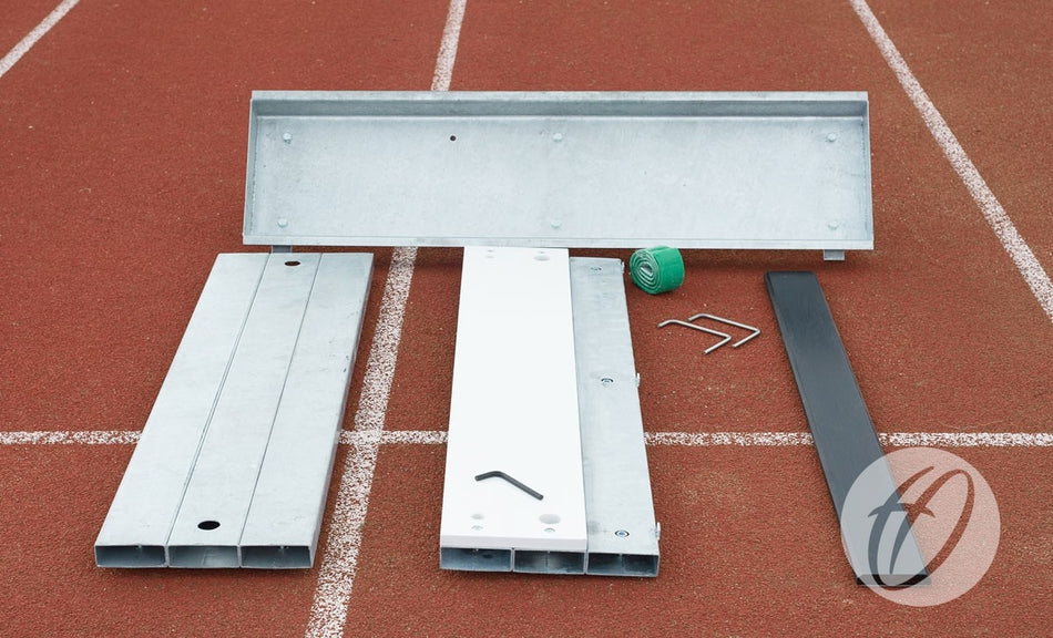 A Harrod Sport Take Off Board with heavy duty steel components, a green tool, and two hex keys is laid out on a red running track with visible white lane markings.