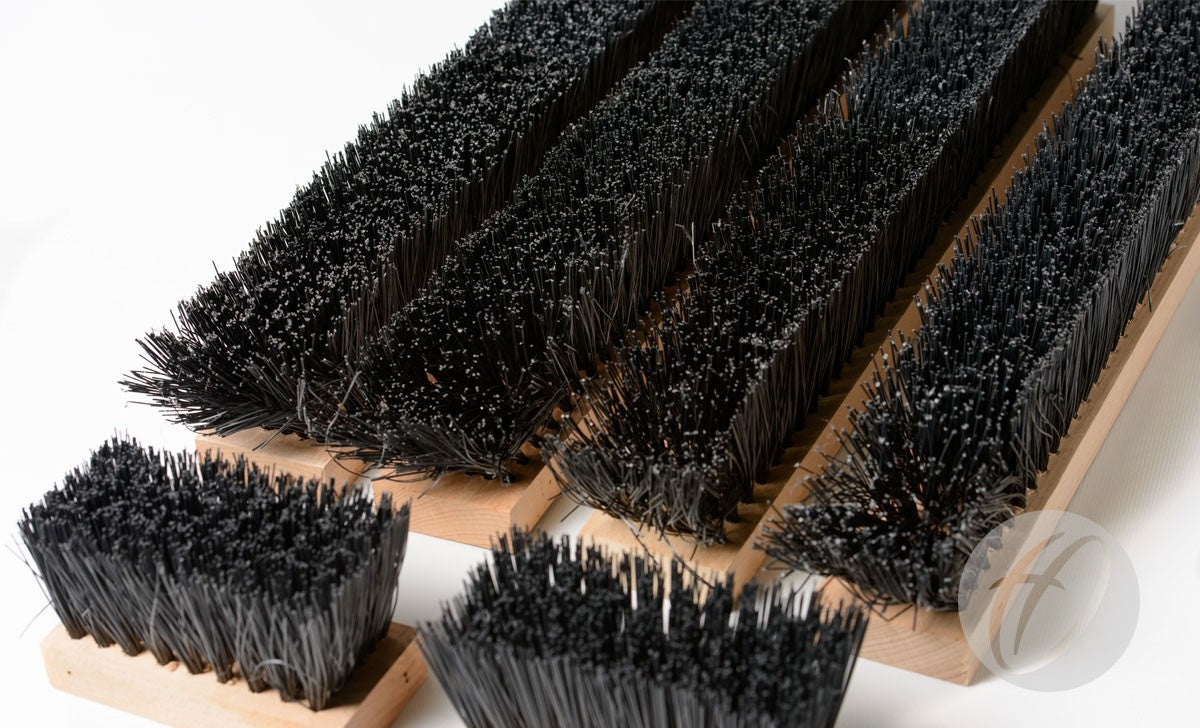Several Harrod Sport Spare Premier Brush Kit 1.1M brushes, featuring dense black bristles and wooden handles, are displayed on a white surface, showcasing the bristle texture and ideal for replacements or spare kits.