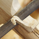 A close-up of a wood file shaping Grade 1 English willow, with curly shavings forming—showcasing the craftsmanship behind the Martin Berrill Sports Custom Made Cricket Bat.