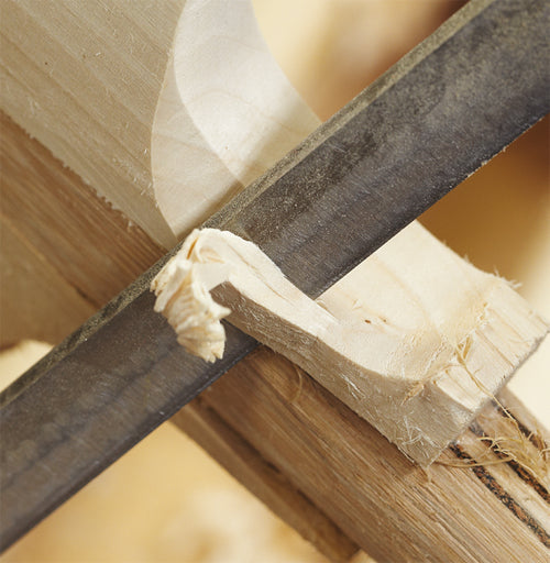 Close-up of a hand saw expertly cutting light-colored wood with shavings curling away—showcasing the craftsmanship behind Martin Berrill Sports’ Custom Made Cricket Bat (Grade 2 Willow).
