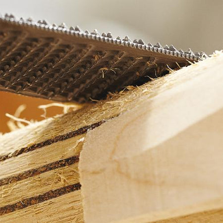 A close-up of a Martin Berrill Sports Custom Made Cricket Bat (Grade 4 Willow) being shaped with a metal rasp tool, with wood shavings and rough edges visible on the bat’s surface.