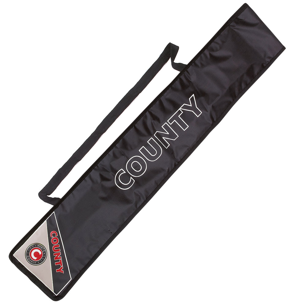 The Hunts County Padded Bat Cover is a black rectangular cover with COUNTY in bold white letters, a shoulder strap, and a triangular Hunts County section with COUNTY and logo on the bottom corner for cricket bat protection.