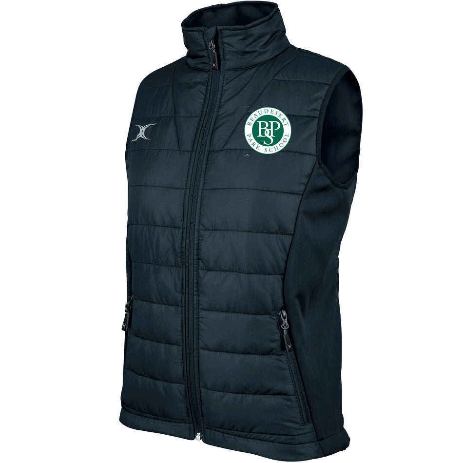 The Gilbert Beaudesert Park School Ladies Pro Bodywarmer is a black, sleeveless, quilted vest with a front zipper, stand-up collar, side panels, a green and white circular logo on the left chest, and a small silver emblem on the right.