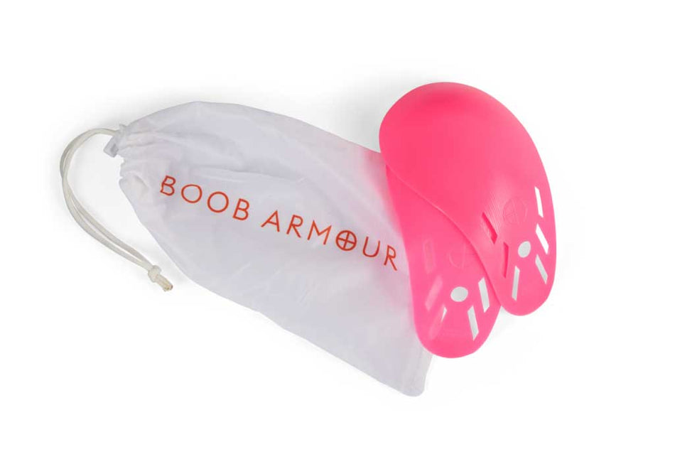 A pair of pink Boob Armour Inserts from Boob Armour are shown next to a white drawstring bag with the brand name in orange.
