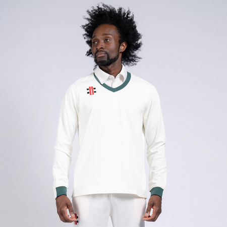 A man with an afro hairstyle wears the Gray Nicolls Oldlands CC Pro Performance Sweater, featuring green trim and a small club logo, over a collared shirt, standing against a plain light background.