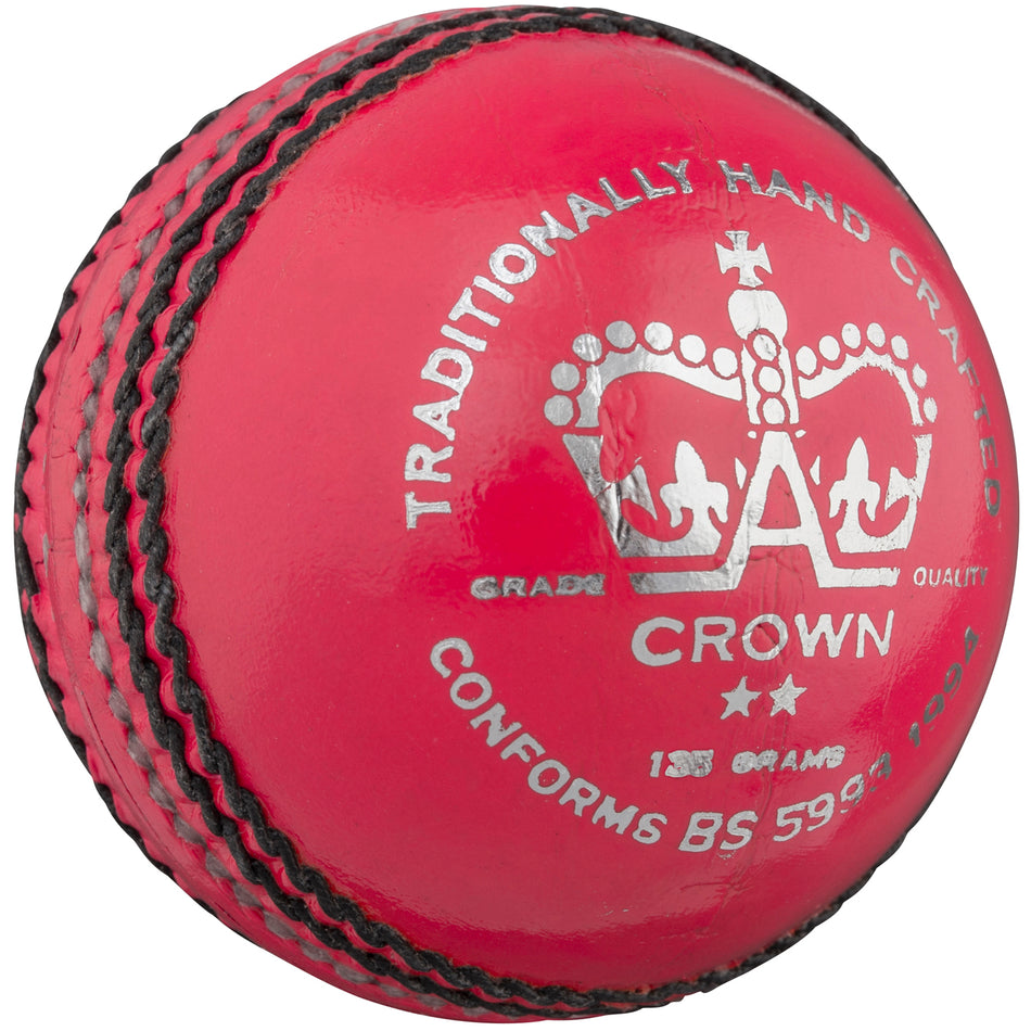 The Gray Nicolls Crown 2 Star Cricket Ball features bright pink Pakistani leather, black stitching, silver text, a crown graphic, and is marked "Traditionally Hand Crafted" and "Conforms BS 599"—ideal for junior players.