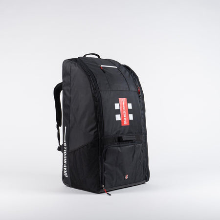 The Gray Nicolls Coach Bag 2026 is a large black sports backpack with red accents and the Gray Nicolls logo, featuring multiple compartments and zippers for all your coaching essentials. Shown on a white background.