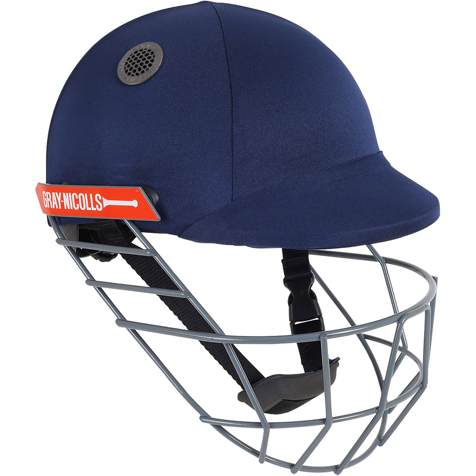The Gray Nicolls Atomic Helmet is a lightweight junior cricket helmet in navy blue, featuring a gray metal face guard, black chin strap, ear vent, and red Gray Nicolls logo—offering perfect protection with comfort.