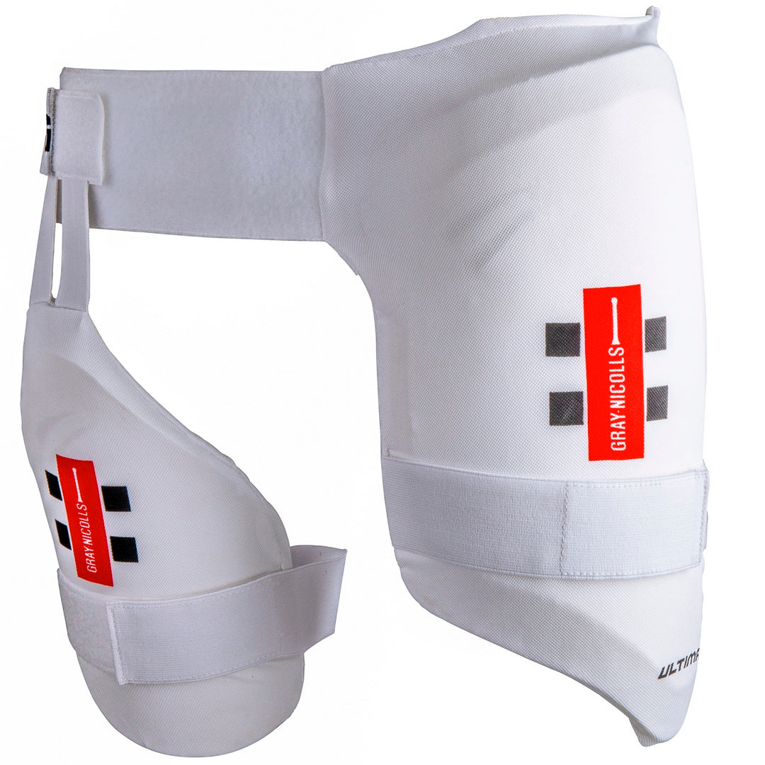 The Gray Nicolls Academy All In One junior cricket thigh pad combines a white, padded design with attached inner thigh protection, adjustable straps, dual level protection, and red and black Gray Nicolls branding for superior leg safety.