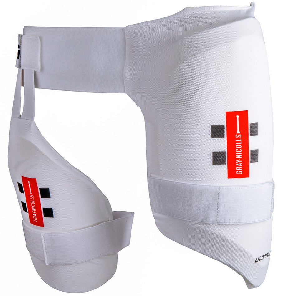 The Gray Nicolls Academy All In One junior cricket thigh pad combines a white, padded design with attached inner thigh protection, adjustable straps, dual level protection, and red and black Gray Nicolls branding for superior leg safety.