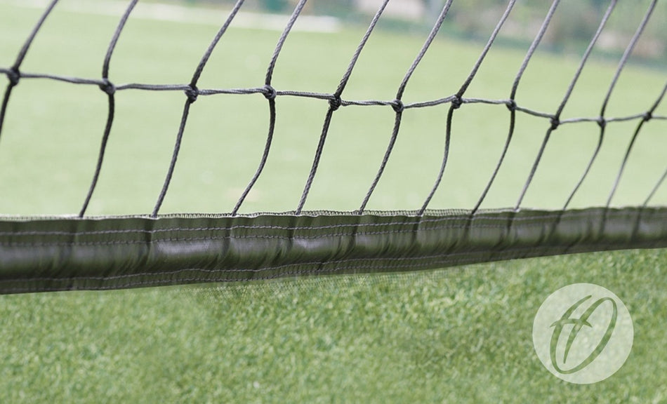 Close-up of Harrod Sport No.16 Cricket Netting - 3M High with 50MM Band, made from durable, UV-resistant black polypropylene, set against green artificial grass. A circular watermark with a stylized H is in the bottom right corner.