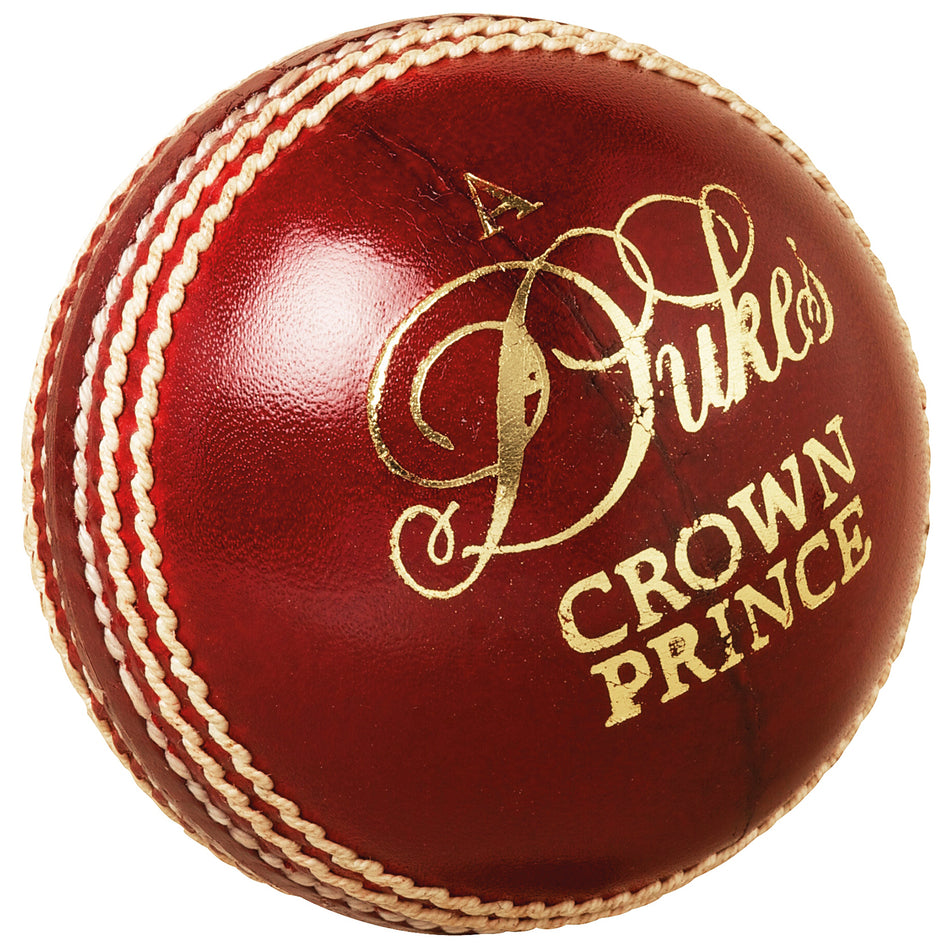 The Dukes Crown Prince A Cricket Ball (Senior) by Dukes is a shiny red ball made from English alum tanned leather, featuring prominent white stitching and "CROWN PRINCE" in gold lettering.