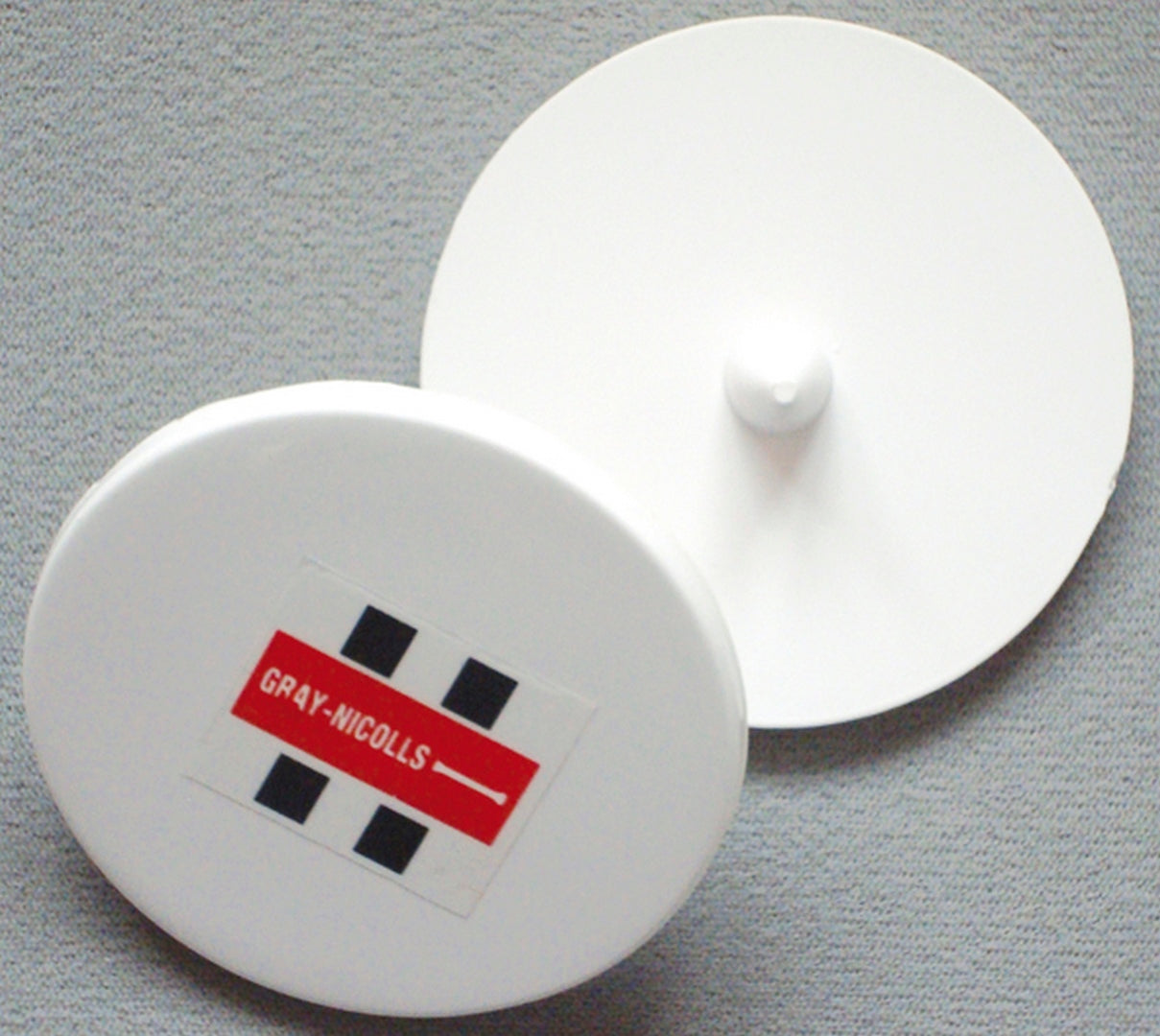 Two Gray Nicolls Bowlers Markers—one showing the red and black Gray Nicolls logo and the other revealing its central knob—rest on a gray surface, ideal for marking run-ups or use during training sessions.