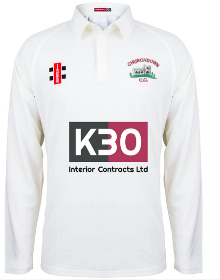 The Churchdown CC Matrix V2 Junior L/S Match Shirt by Gray Nicolls is a white junior cricket shirt featuring the Churchdown C.C. logo, K30 Interior Contracts Ltd as central sponsor, and two smaller logos on the chest and left shoulder.