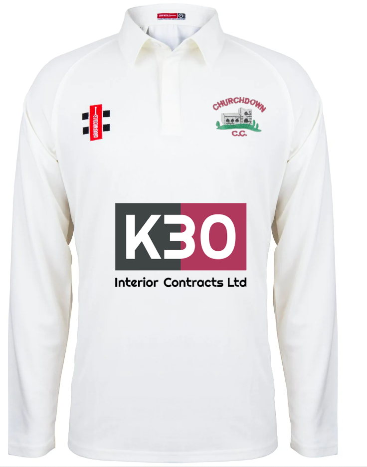 The Churchdown CC Matrix V2 Junior L/S Match Shirt by Gray Nicolls is a white junior cricket shirt featuring the Churchdown C.C. logo, K30 Interior Contracts Ltd as central sponsor, and two smaller logos on the chest and left shoulder.