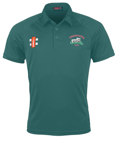 The Churchdown CC Matrix V2 Polo Shirt by Gray Nicolls is a teal short-sleeve polo with collar, button placket, embroidered logos—a red and white patch and CHAPELSMITH C.C. crest with building graphic—and Matrix V2 moisture-wicking fabric.
