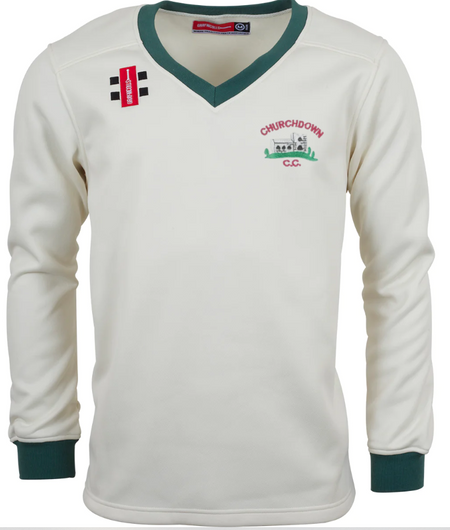 The Gray Nicolls Churchdown CC Pro Performance Sweater is a white long-sleeve cricket sweater with green cuffs and collar, a club logo and illustration on the left chest, and two black bars with a red rectangle on the right shoulder.