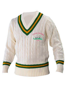 The Martin Berrill Sports Churchdown CC Long Sleeve Sweater is cream-colored with cable-knit design and green/yellow stripes on the V-neck, cuffs, and waist. Features embroidered text and a cricket pavilion club logo on the chest.