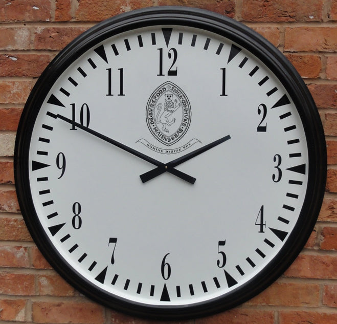The Martin Berrill Sports Pavilion Sports Club House Clock features a large round white face with black numbers and hands set to 10:10, a crest with text at the top center, and is designed for external mounting on brick walls.