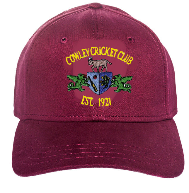 The Cowley CC Maroon Baseball Cap by Martin Berrill Sports features the club logo with a ram, two green dragons, a blue crest, and "Cowley Cricket Club Est. 1921" embroidered on the front.