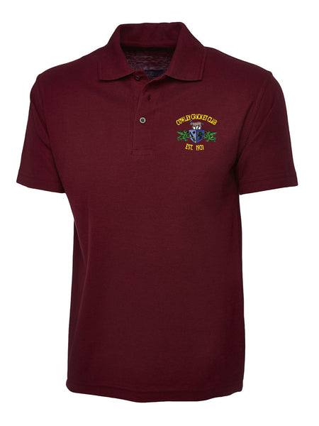 The Cowley CC Polo Shirt by Martin Berrill Sports is a maroon, short-sleeved polyester-cotton polo with a collar and two buttons, featuring an embroidered yellow and green Cowley Cricket Club Est. 1971 logo on the left chest.