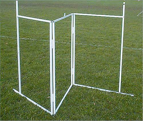 The Martin Berrill Sports Crease Marker features a white folding steel frame forming a three-sided structure, open on one side, standing on green grass in an open field—ideal for marking cricket creases.