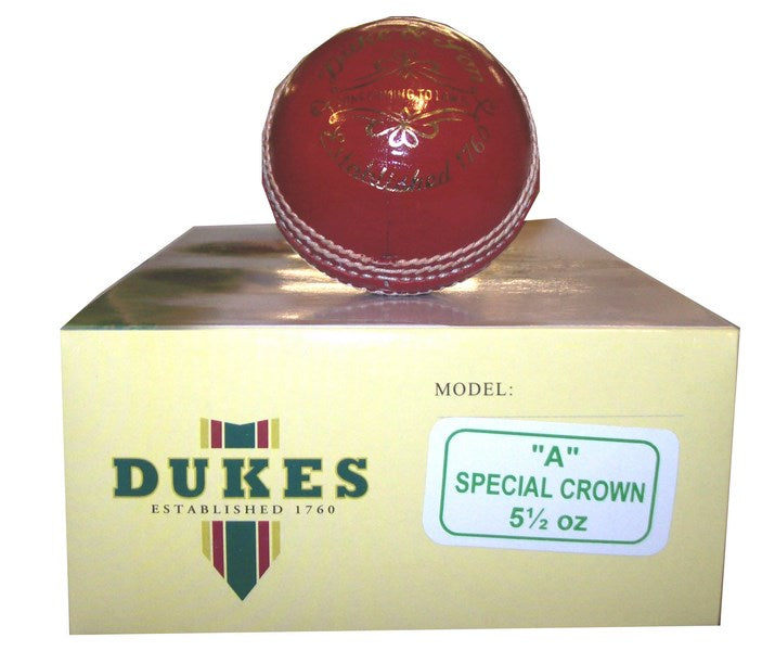 A red Dukes Special Crown Cricket Ball (Senior) with white stitching sits on a yellow box labeled "Dukes Established 1760" and "Model: Special Crown 5½ oz," showcasing its quality as a trusted English leather ball.