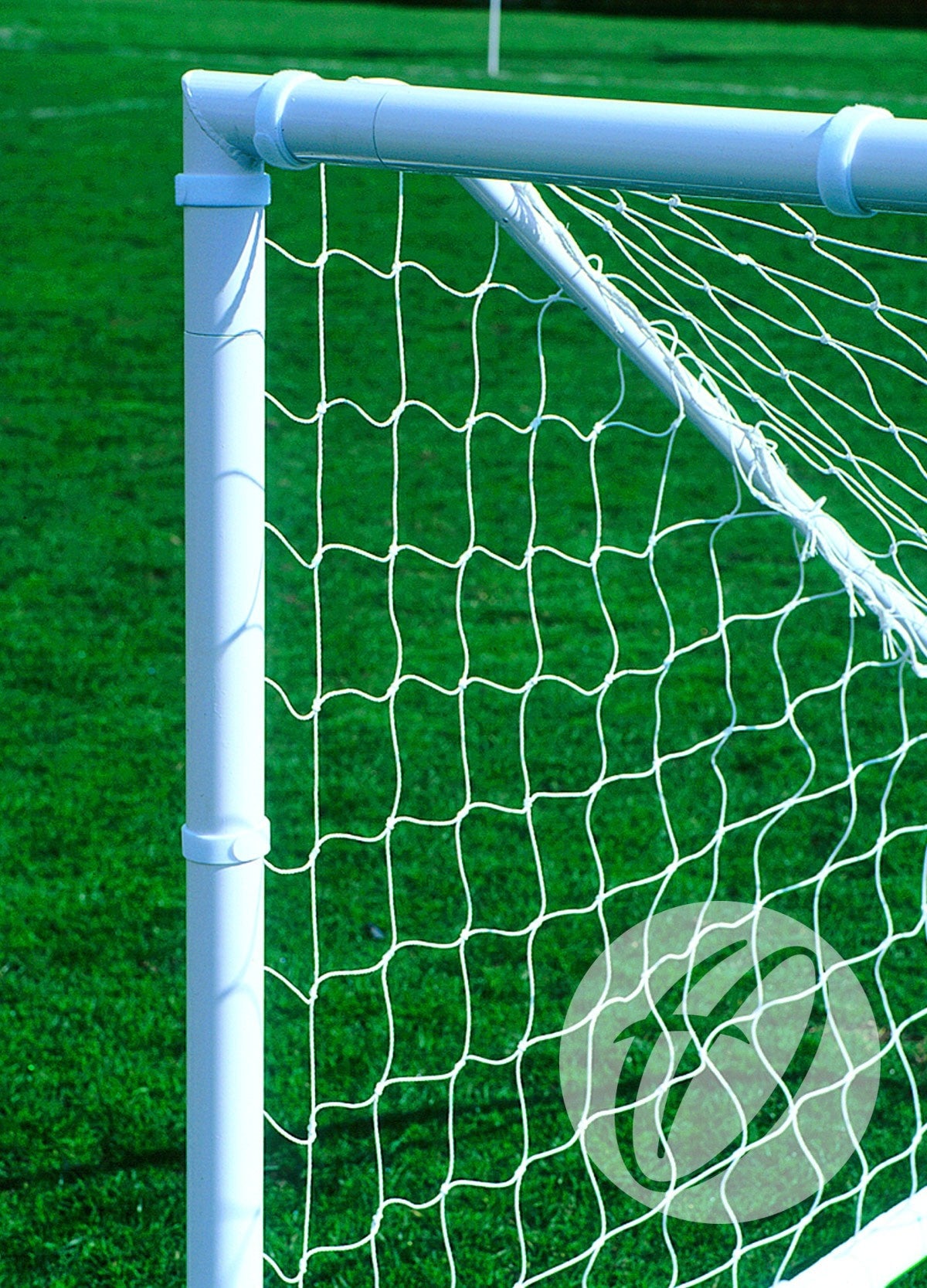 Close-up of white goal posts with netting secured by Harrod Sport 200mm Senior Football Net Ties (40 pack) on a green grass field, with hook-and-loop fasteners visible and part of another goalpost in the background.