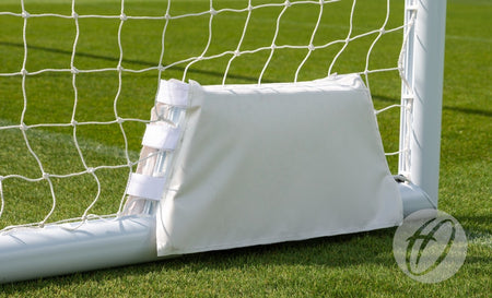 A Harrod Sport 4G Swivel Portagoal - Wheel Protection Pad is shown attached to the bottom corner of a soccer goalpost on green grass, with netting visible in the background.