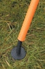 A close-up of a Precision Training Flexi Boundary Pole accessory, featuring an orange handle and black circular base, rests on green grass—ideal for use with Precision Training Flexi Boundary Poles & Bag.