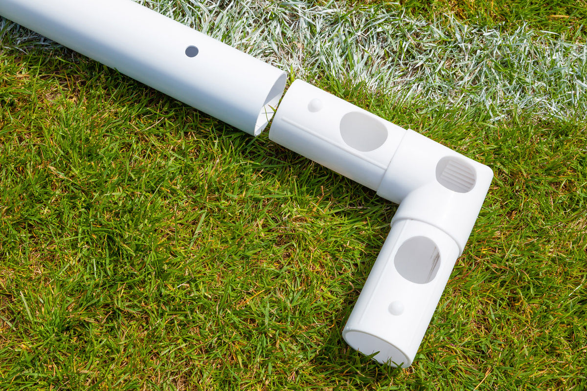 Close-up of high impact uPVC pipes forming a right angle joint on green grass by a white line—part of the durable Samba Sports Samba Match Goal 8 x 6 football goal.