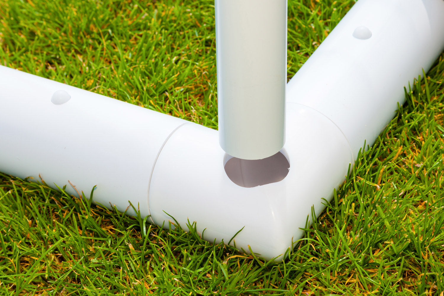 Close-up of durable uPVC pipes from the Samba Sports Samba Match Goal 8 x 6, connecting securely at a corner joint on green grass. A vertical pipe fits neatly into the horizontal piece, forming part of the sturdy goal frame.