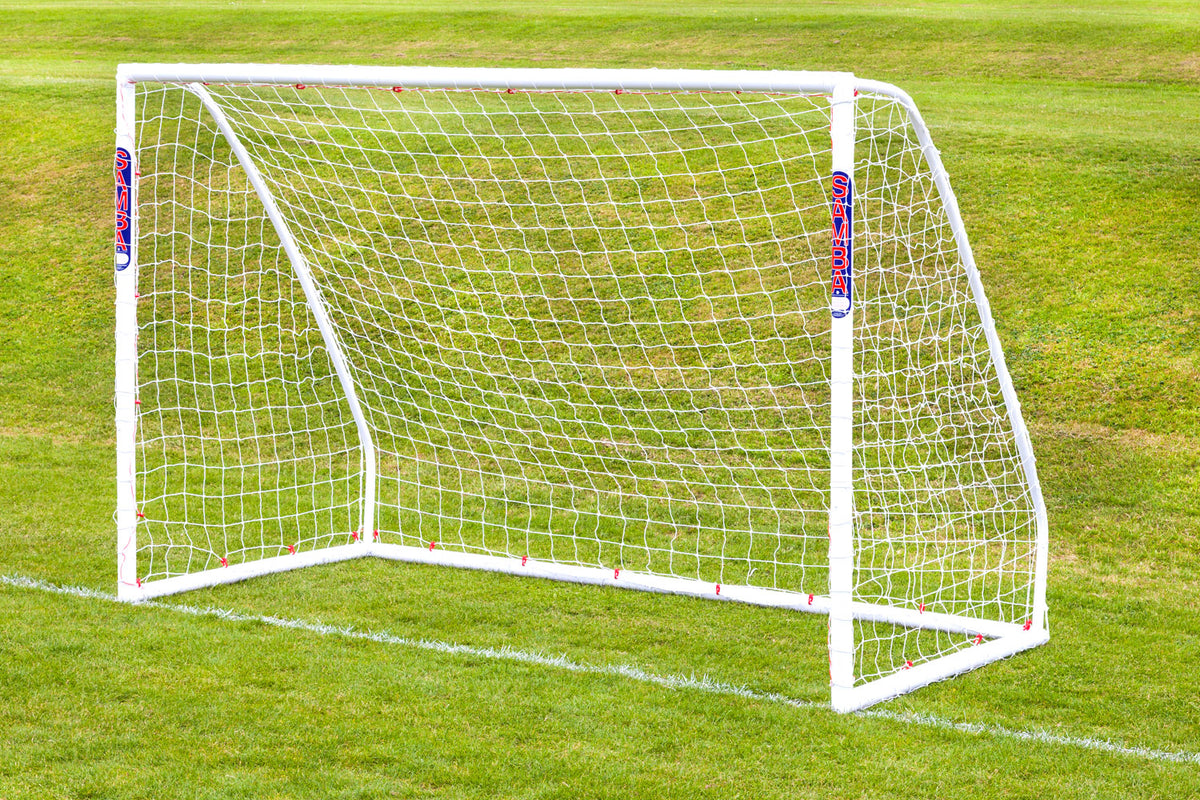 A Samba Sports Futsal Match Goal 3m x 2m with a net is set up on green grass. Its high-impact uPVC frame and red and blue branding stand out against the well-maintained field.