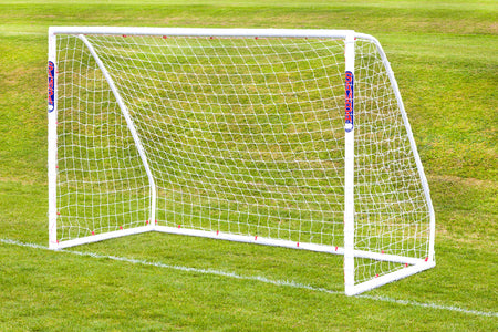 A Samba Sports Futsal Match Goal 3m x 2m with a net is set up on green grass. Its high-impact uPVC frame and red and blue branding stand out against the well-maintained field.