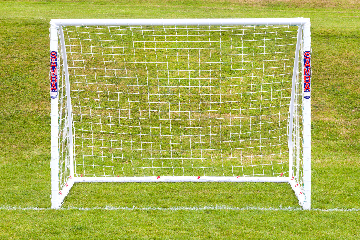 A Samba Sports Match Goal 8 x 6, made from high impact uPVC, stands on green grass just behind a white line. The word SAMBA appears in red on both posts. The goal measures 8ft x 6ft and is white in color.