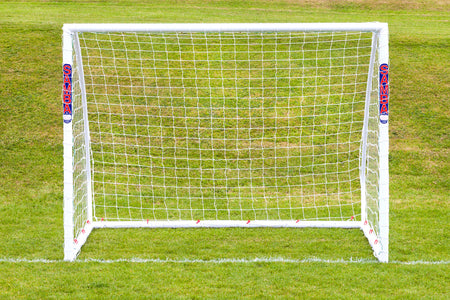 A Samba Sports Match Goal 8 x 6, made from high impact uPVC, stands on green grass just behind a white line. The word SAMBA appears in red on both posts. The goal measures 8ft x 6ft and is white in color.